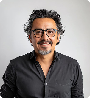 Smiling man with glasses, curly hair, and a goatee wearing a black button-up shirt against a plain background.